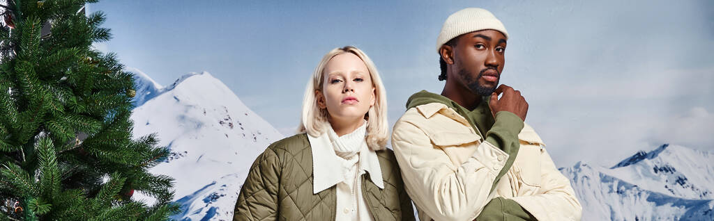 gyönyörű multikulturális pár pózol meleg kabát és nézi a kamera, téli divat, banner - Fotó, kép