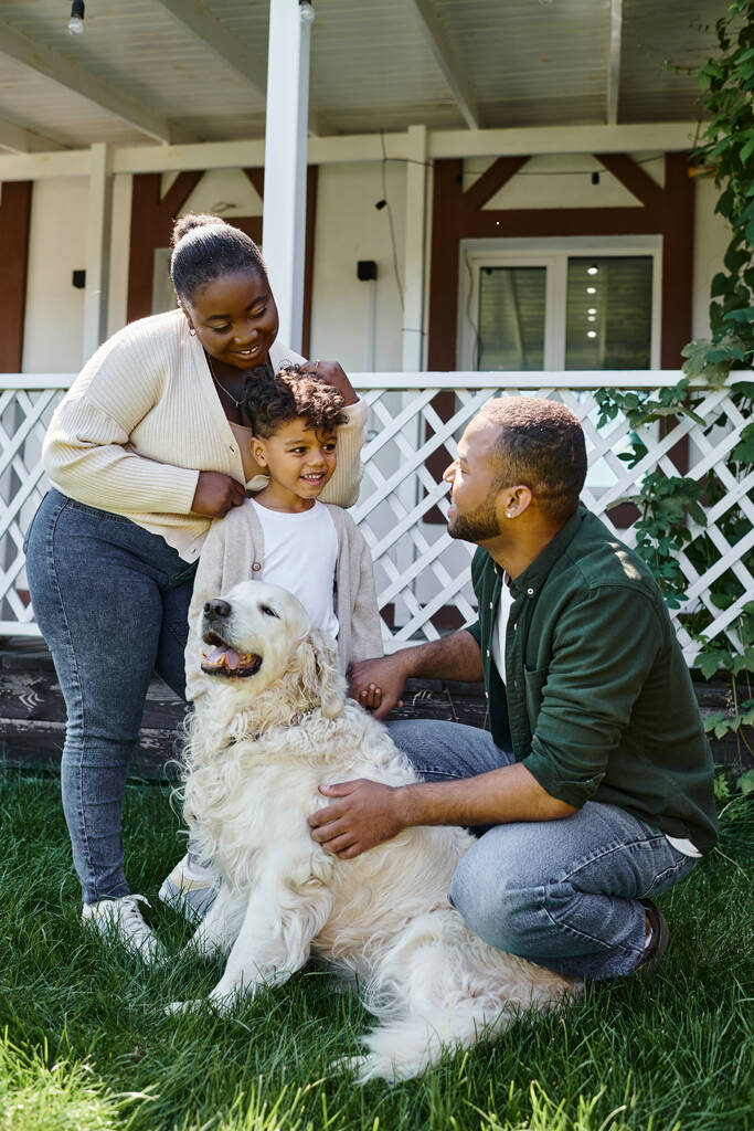 Neşeli Afro-Amerikan ailesi evlerinin arka bahçesinde köpekle oynuyor. - Fotoğraf, Görsel