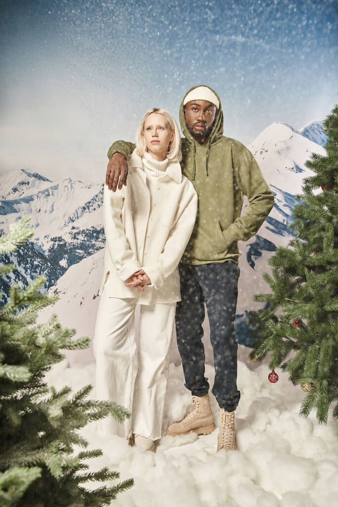 atractiva pareja posando bajo la nieve y usando ropa de invierno con estilo, moda y estilo - Foto, imagen