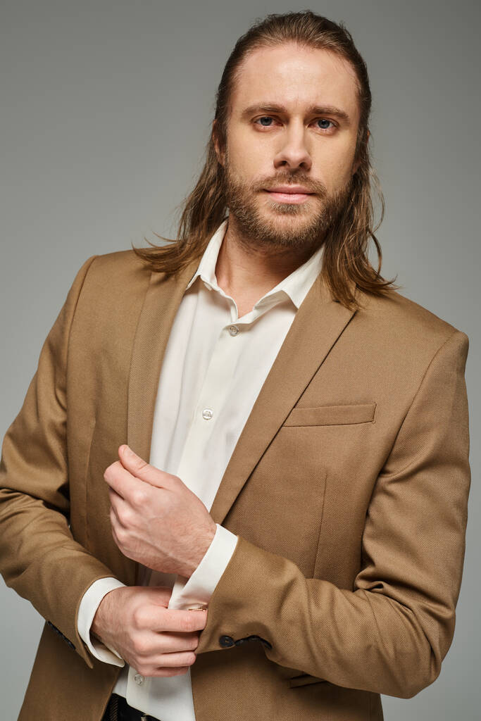 灰色の背景,正式な服装にブレーザーでポーズするひげと長い髪のハンサムなビジネスマン - 写真・画像