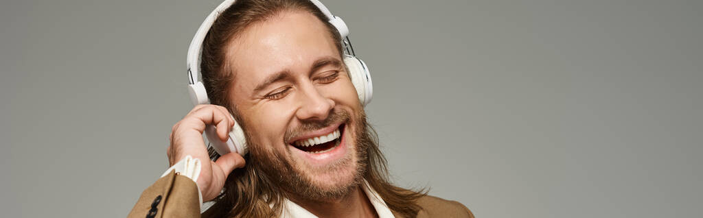 vidám szakállas üzletember fejhallgatóval zenét hallgat szürke háttérrel, banner - Fotó, kép
