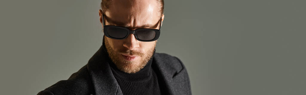 портрет бородатого чоловіка в модних сонцезахисних окулярах і чорний одяг позує на сірому тлі, банер - Фото, зображення