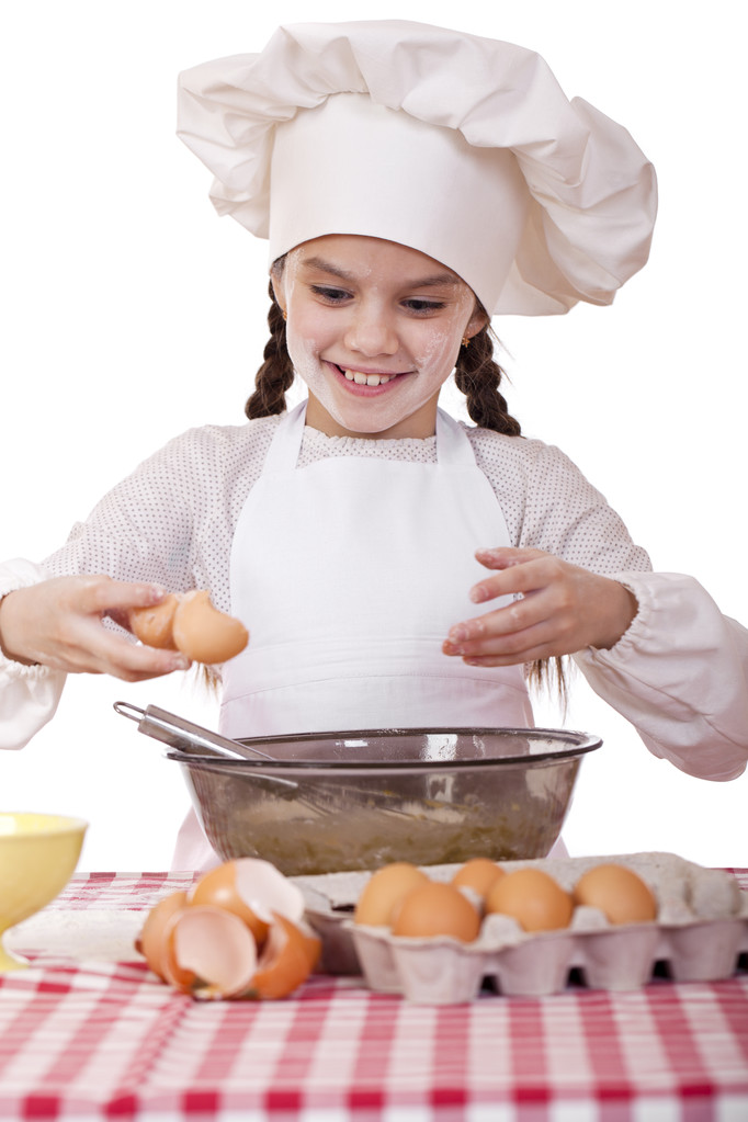Küçük aşçı kız beyaz bir önlük yumurtaları derin bir tabak içinde tatili. - Fotoğraf, Görsel