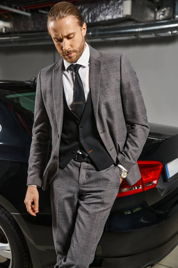 добре виглядає вишуканий чоловік в елегантному костюмі позує біля своєї машини з рукою в кишені, бізнес-концепція - Фото, зображення