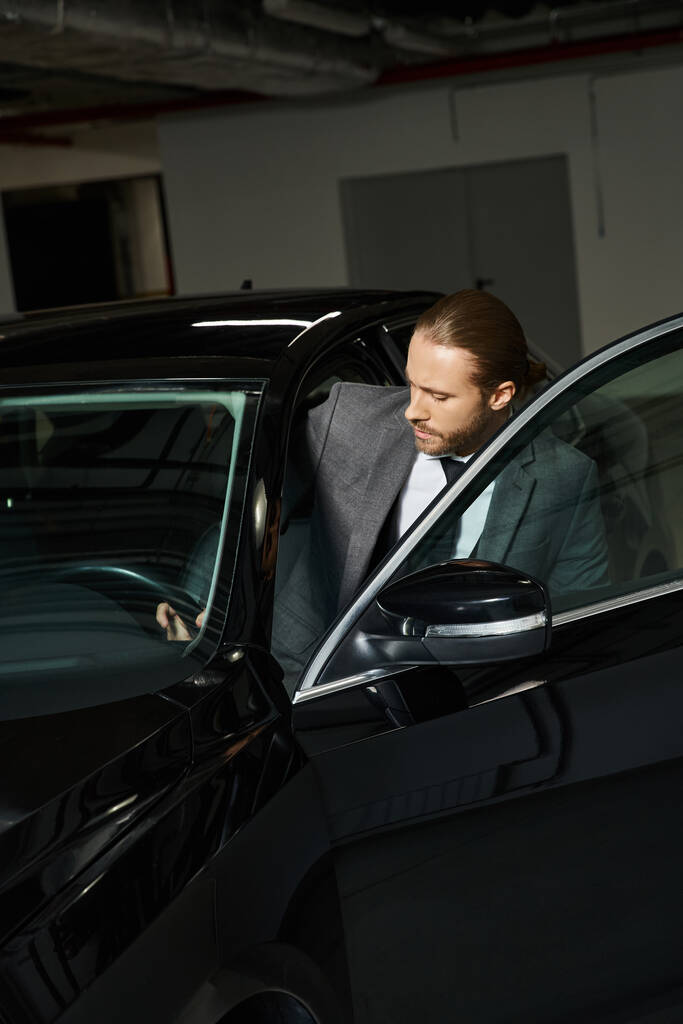 красивий елегантний чоловік з хвостом у шикарному розумному костюмі, що потрапляє в його машину, бізнес-концепція - Фото, зображення
