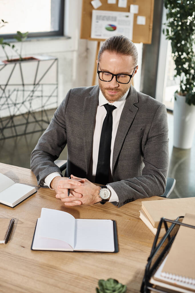 hombre de negocios reflexivo en ropa formal mirando el cuaderno en blanco en el lugar de trabajo en la oficina moderna - Foto, Imagen