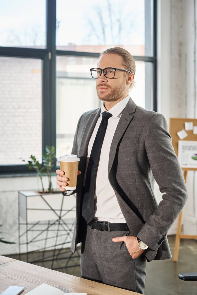 オフィスのポケットに手を置いて行くためにコーヒーを保持する眼鏡の優雅なビジネスマン - 写真・画像