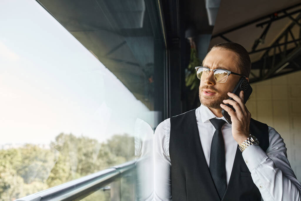 ansprechender gut aussehender Mann mit gepflegtem Stil, der telefonisch neben dem Fenster spricht, Geschäftskonzept - Foto, Bild
