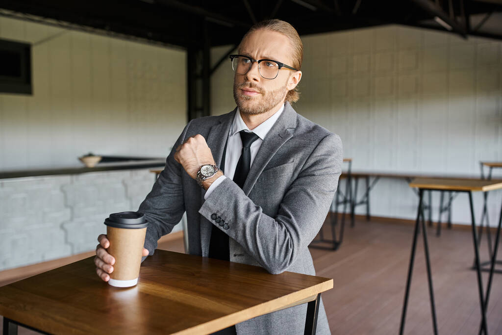 knappe elegante professional in smart suit met koffiebeker en weg te kijken, business concept - Foto, afbeelding