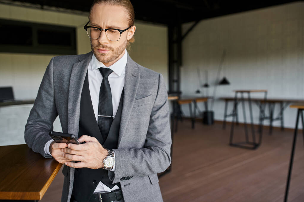 handsome professional in smart gray suit looking attentively at his mobile phone, business concept - Photo, Image