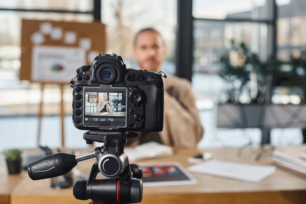 επιλεκτική εστίαση επαγγελματικής ψηφιακής φωτογραφικής μηχανής κοντά σε επιχειρηματία που καταγράφει περιεχόμενο βίντεο στο γραφείο - Φωτογραφία, εικόνα