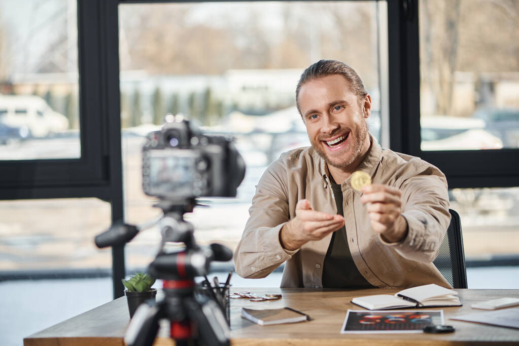 vreugdevolle succesvolle ondernemer tonen Bitcoin op digitale camera en het opnemen van video blog in kantoor - Foto, afbeelding