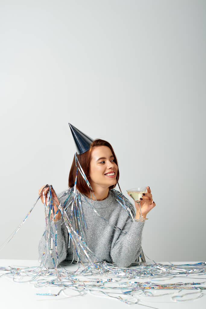 счастливая женщина в шапочке с мишурой на голове, держа бокал шампанского во время празднования Рождества - Фото, изображение