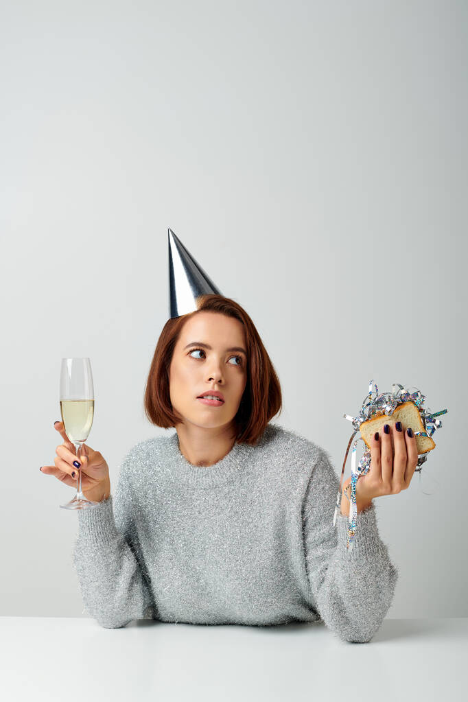 young woman in party cap holding champagne glass and sandwich with tinsel, Merry Christmas concept - Photo, Image