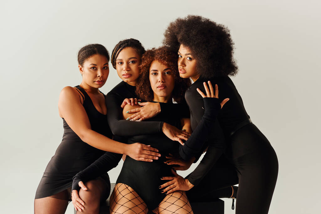 ελκυστικές αφρικανικές αμερικανίδες με μαύρες γοητευτικές ενδυμασίες ποζάρουν σε μαύρο κύβο, έννοια της μόδας - Φωτογραφία, εικόνα