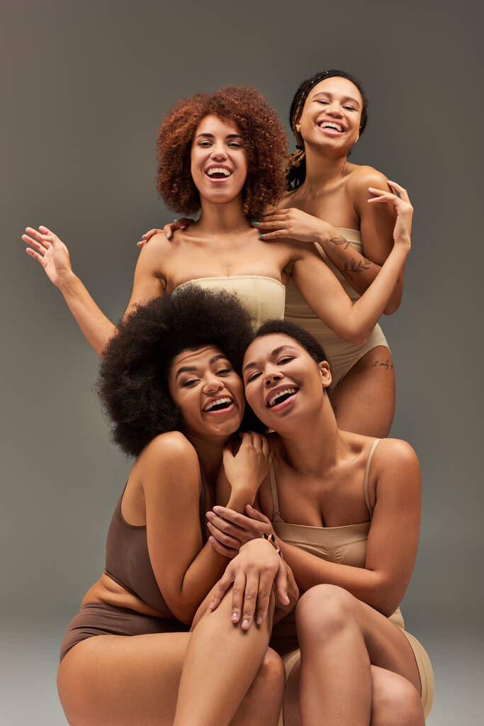ansprechende fröhliche afrikanisch-amerikanische Frauen in bequemer Unterwäsche, die viel Spaß miteinander haben, Mode - Foto, Bild