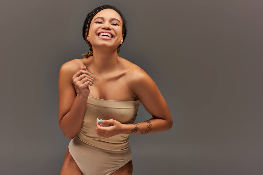 alegre modelo feminino afro-americano em cuecas pastel bege tendo grande momento, conceito de moda - Foto, Imagem