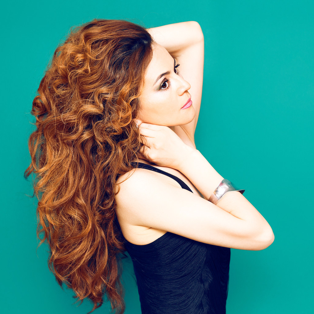 Modedame mit langen roten lockigen Haaren auf blauem Hintergrund - Foto, Bild