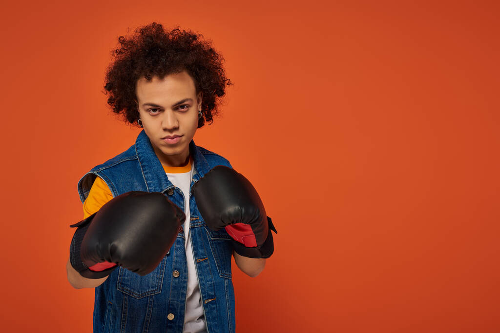 good looking sporty african american man posing lively in boxing gloves on orange background - Photo, Image