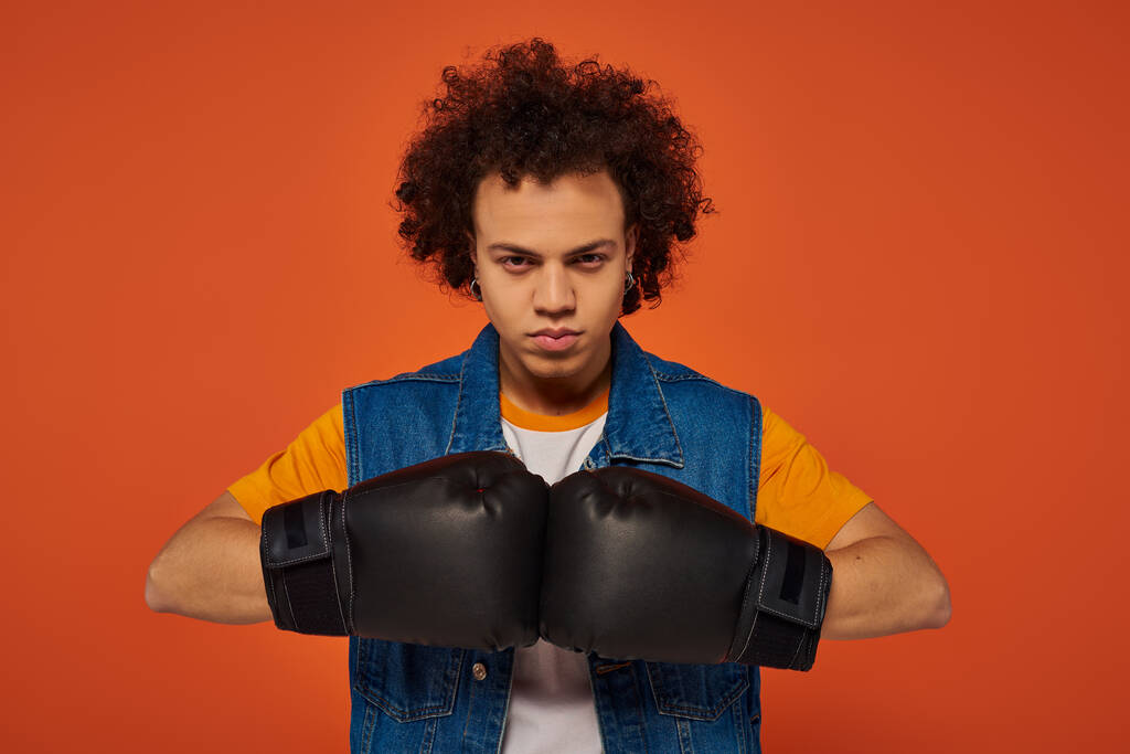 красивый спортивный африканский американец, активно позирующий в боксёрских перчатках на оранжевом фоне - Фото, изображение