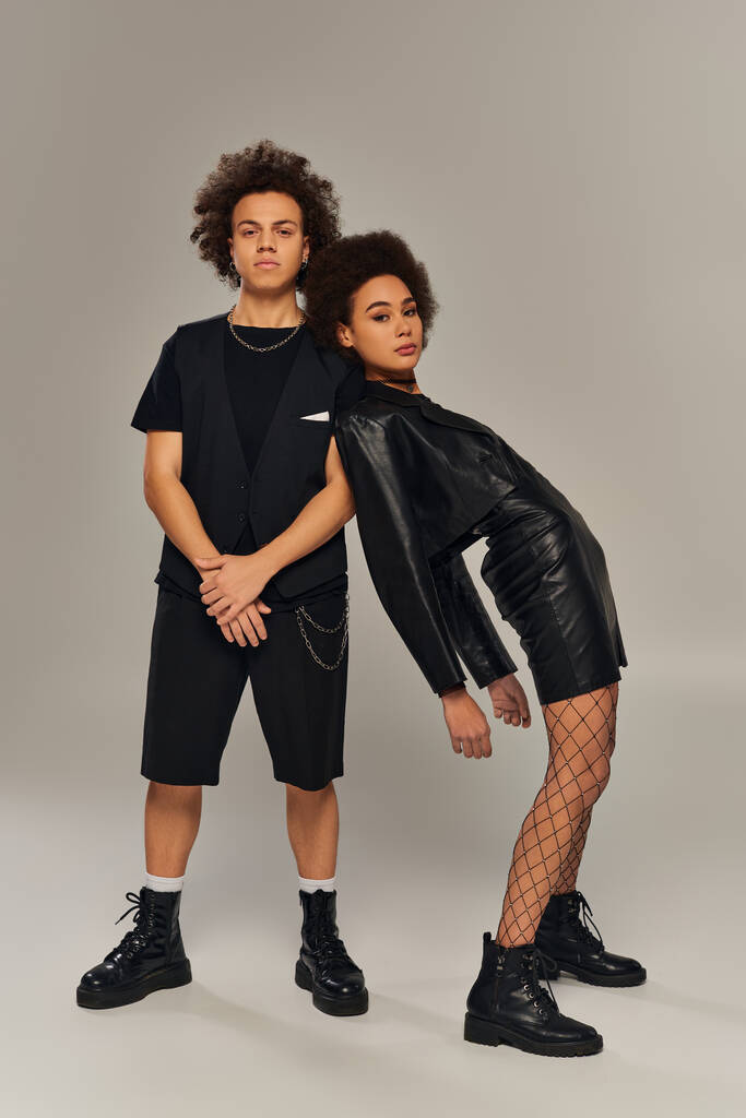 привлекательные стильные африканские американские братья и сестры в модных черных нарядах позируют на сером фоне - Фото, изображение