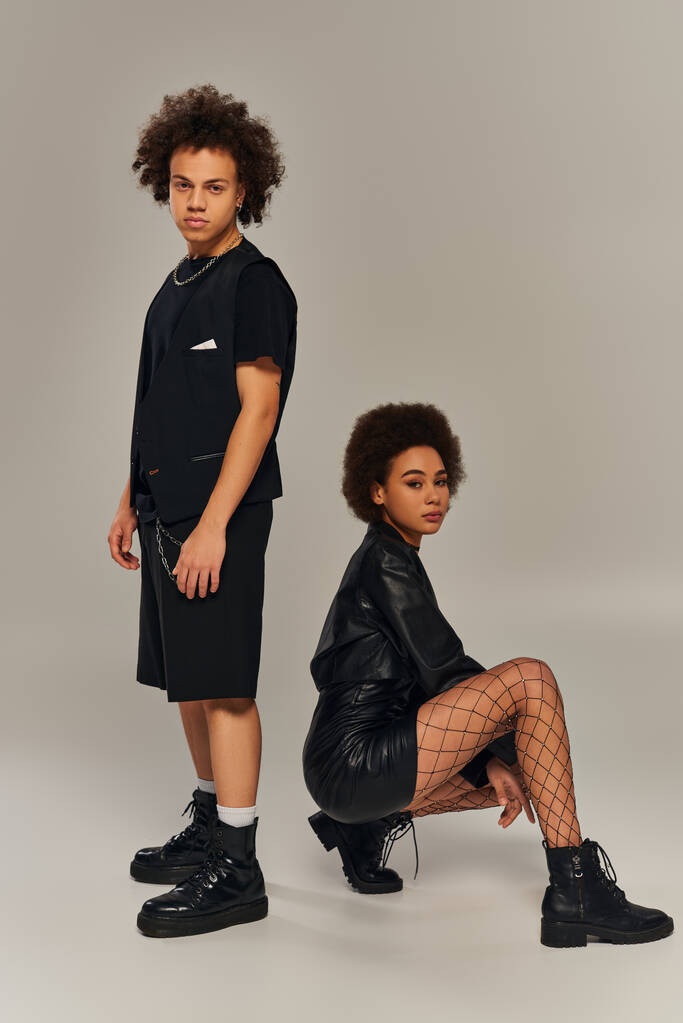 vonzó afro-amerikai testvére és nővére fekete ruhák guggoló szürke háttér - Fotó, kép