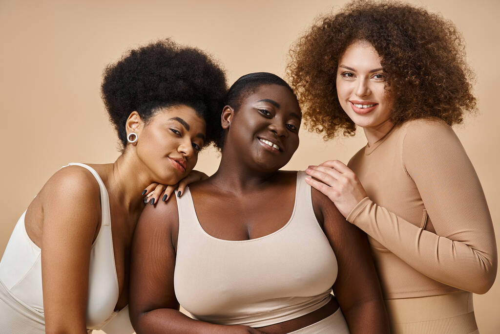 multiethnisch kurvige und körperbetonte Frauen in Unterwäsche auf beigem Hintergrund, natürliche Plus-Size-Schönheit - Foto, Bild