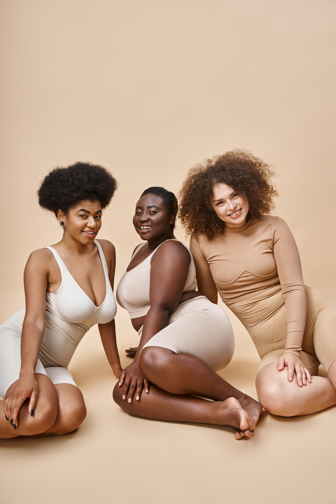 bájos multiracial nők fehérnemű pózol bézs háttér, plusz méret elegancia és szépség - Fotó, kép