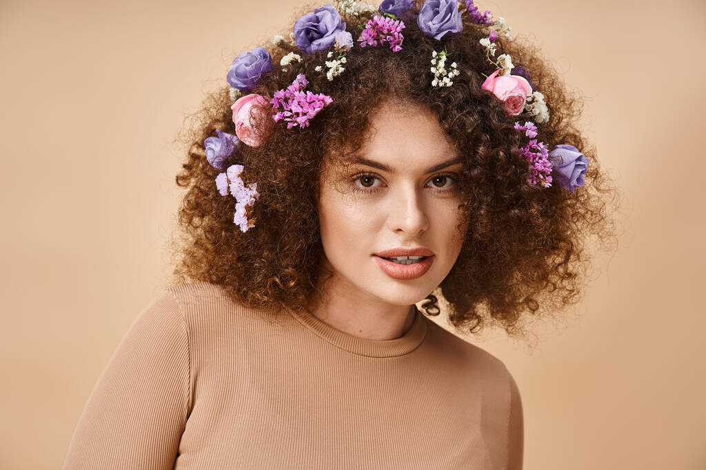 портрет щасливої жінки з барвистими квітами у волоссі, посміхаючись на камеру на бежевій, природній красі - Фото, зображення