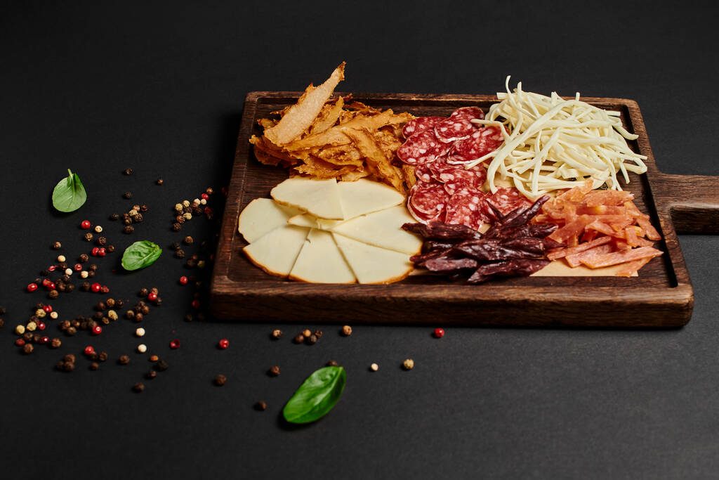 Peynir seçmeli şarküteri panosunun üst görüntüsü, siyah üzerine kurutulmuş sığır eti ve salam, antipasto. - Fotoğraf, Görsel