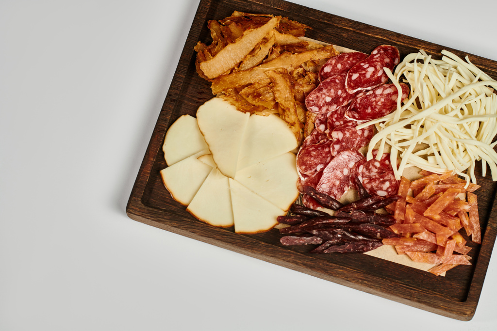 Şarküteri kurulu gurme peynir seçimi, kurutulmuş sığır eti ve salam dilimleri ile gri arka planda - Fotoğraf, Görsel