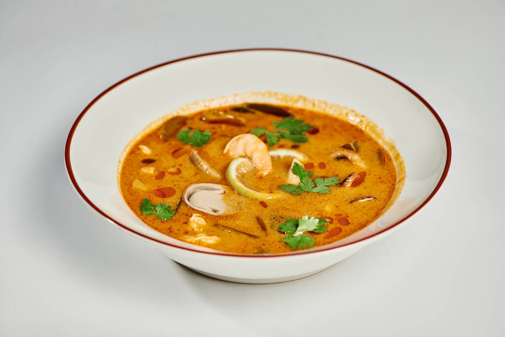 tasty Thai soup with coconut milk, shrimp, lemongrass and cilantro on grey backdrop, Tom yum - Photo, Image