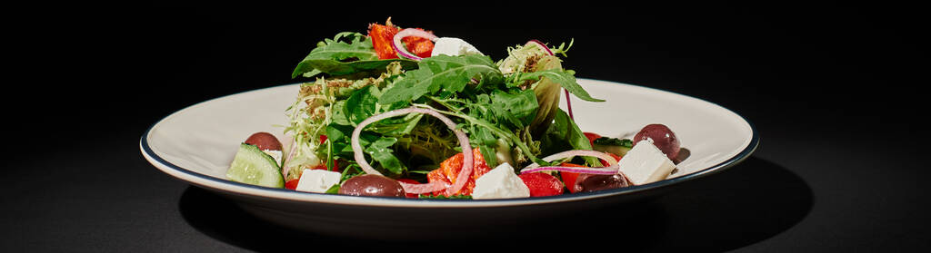 gezond eten banner, heerlijke Griekse salade met feta kaas, rode ui, arugula bladeren op zwart - Foto, afbeelding