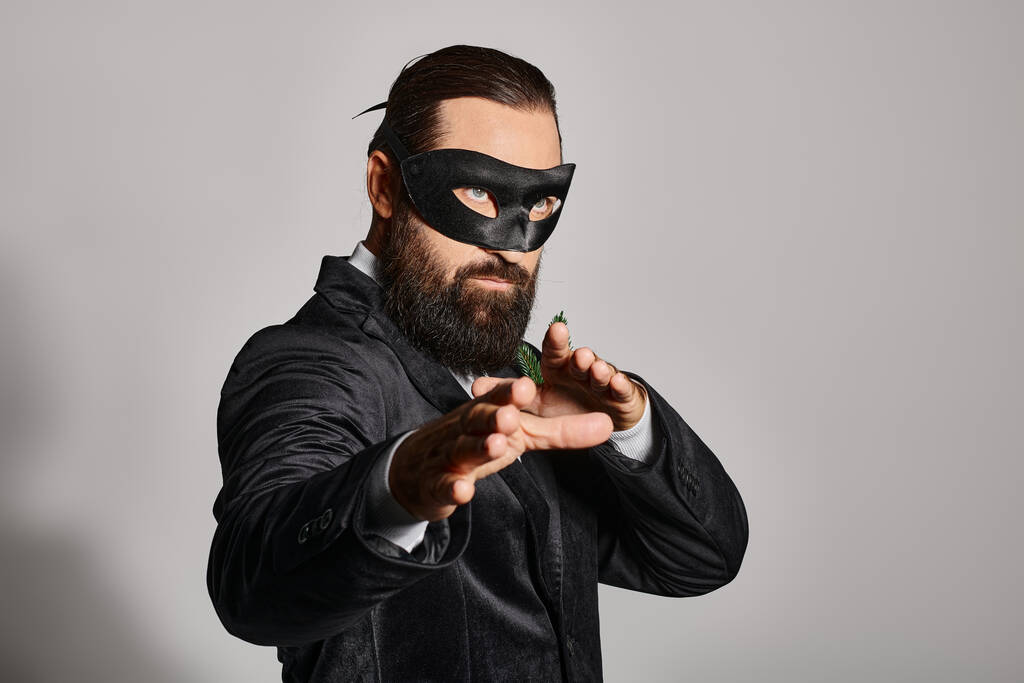 Bola de máscaras de Natal, homem barbudo bonito em máscara de carnaval e terno elegante em pano de fundo cinza - Foto, Imagem