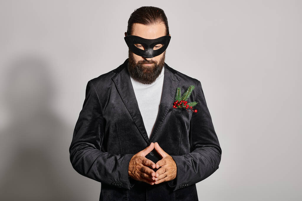 Ballo in maschera, uomo barbuto concentrato in maschera di carnevale ed elegante abbigliamento formale su sfondo grigio - Foto, immagini
