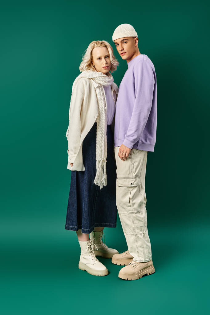 full length of tall stylish man standing with blonde woman in winter attire on turquoise backdrop - Photo, Image