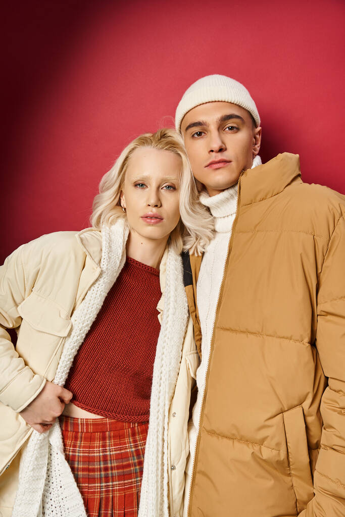 stílusos férfi és nő divatos téli felsőruházat pózol együtt piros háttér, téli divat - Fotó, kép