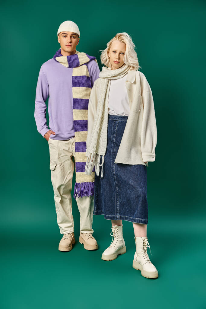trendy colors, man in stripped scarf and beanie posing with beautiful woman on turquoise backdrop - Photo, Image