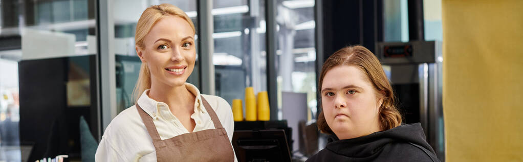 χαρούμενος διαχειριστής καφέ χαμογελώντας κοντά σε νεαρή γυναίκα με διανοητική αναπηρία, οριζόντιο πανό - Φωτογραφία, εικόνα
