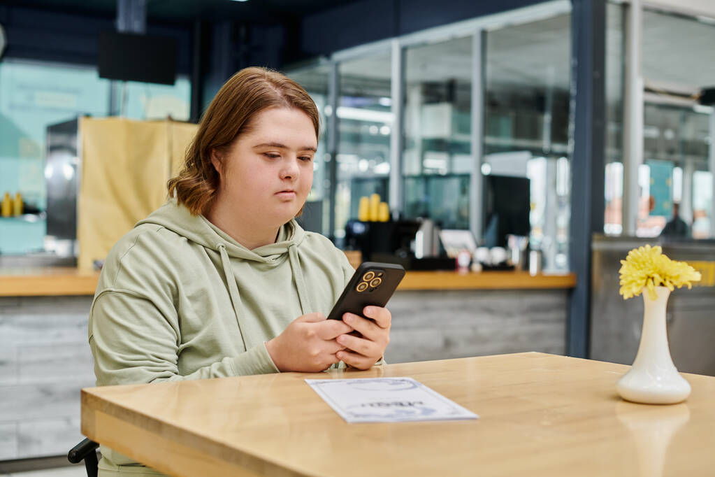 mujer joven con mensajes de trastorno mental en el teléfono móvil cerca de la tarjeta de menú en la mesa en la cafetería - Foto, imagen