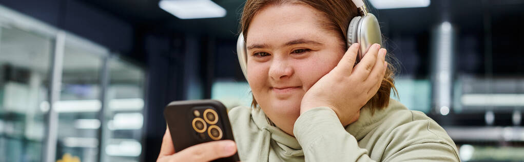 happy woman with mental disorder listening music in headphone and holding smartphone in cafe, banner - Photo, Image