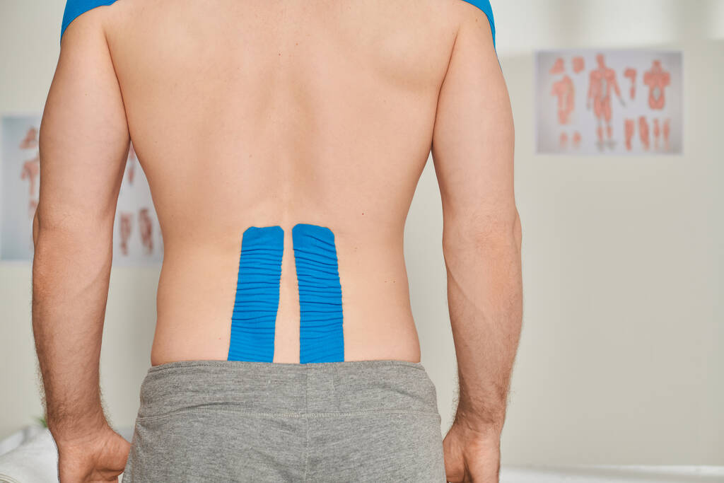 cropped back view of man in gray sweatpants with kinesiological tapes on his back, healthcare - Photo, Image
