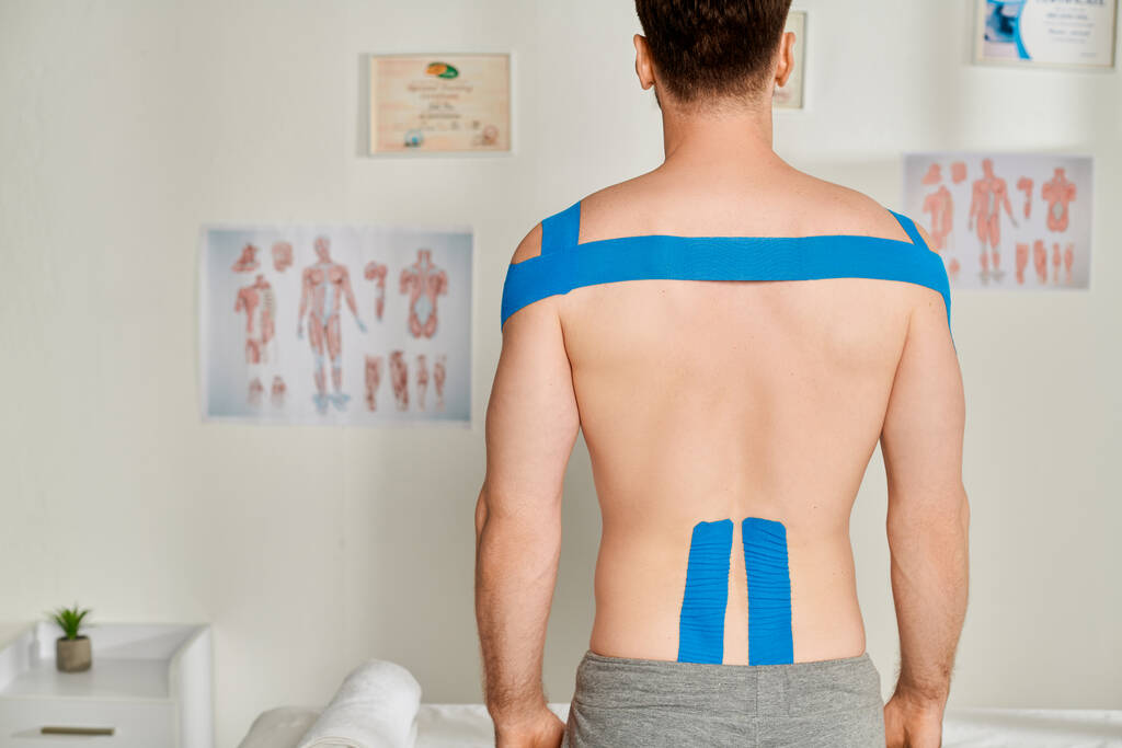 вид ззаду пацієнта чоловічої статі під час призначення з кінезіологічними стрічками на спині і плечах - Фото, зображення