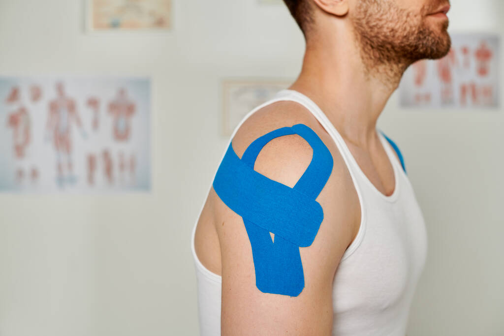 vista ritagliata dell'uomo con nastri cinesiologici sulla spalla durante l'appuntamento, assistenza sanitaria - Foto, immagini