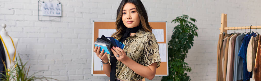 jovem estilista asiático elegante com amostras de cor olhando para a câmera no atelier privado, banner - Foto, Imagem