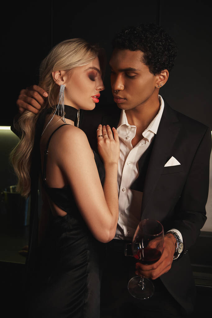 attrayant couple multiracial aimant se préparant à embrasser allègrement, verre de vin rouge à la main - Photo, image