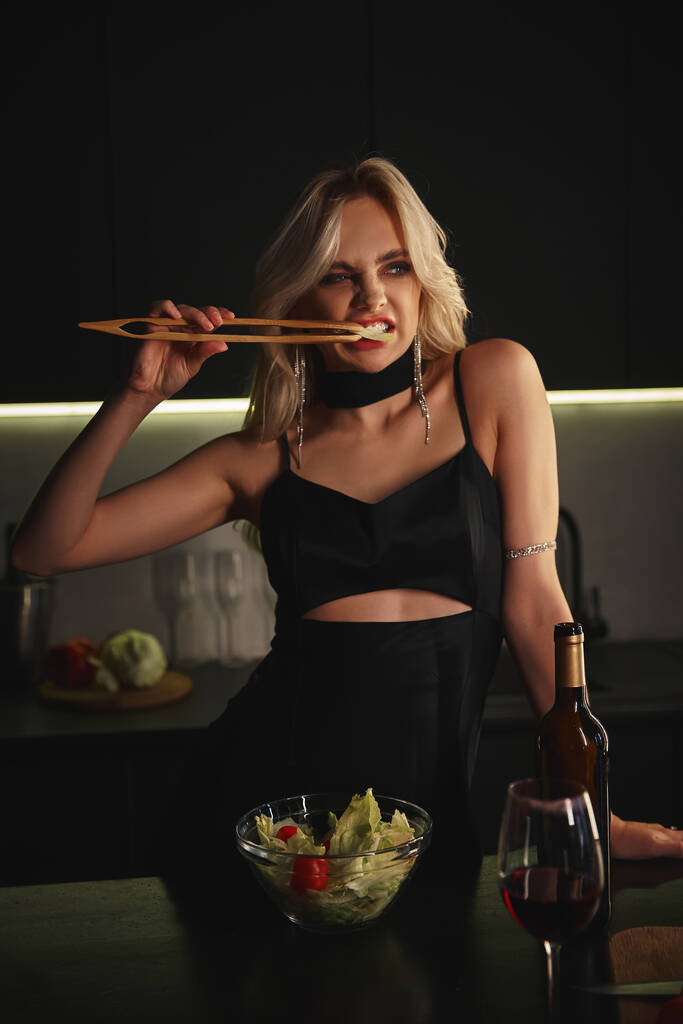 csinos vonzó szőke nő fekete elegáns ruha eszik friss saláta evőpálcikával - Fotó, kép