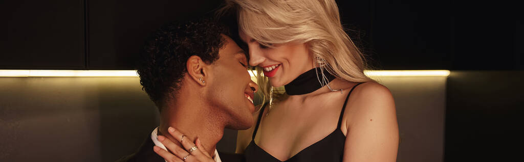 couple interracial joyeux dans des tenues élégantes chic posant ensemble et serrant chaudement, bannière - Photo, image