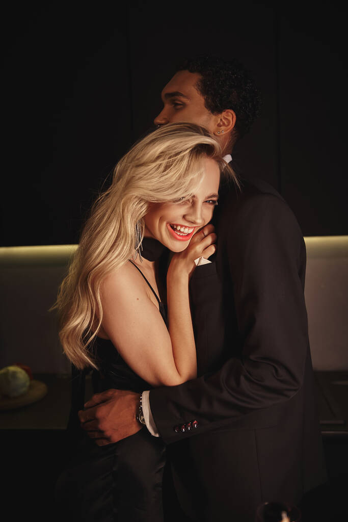 vrolijk mooi vrouw met blond haar glimlachen en knuffelen haar Afrikaans amerikaans vriendje - Foto, afbeelding