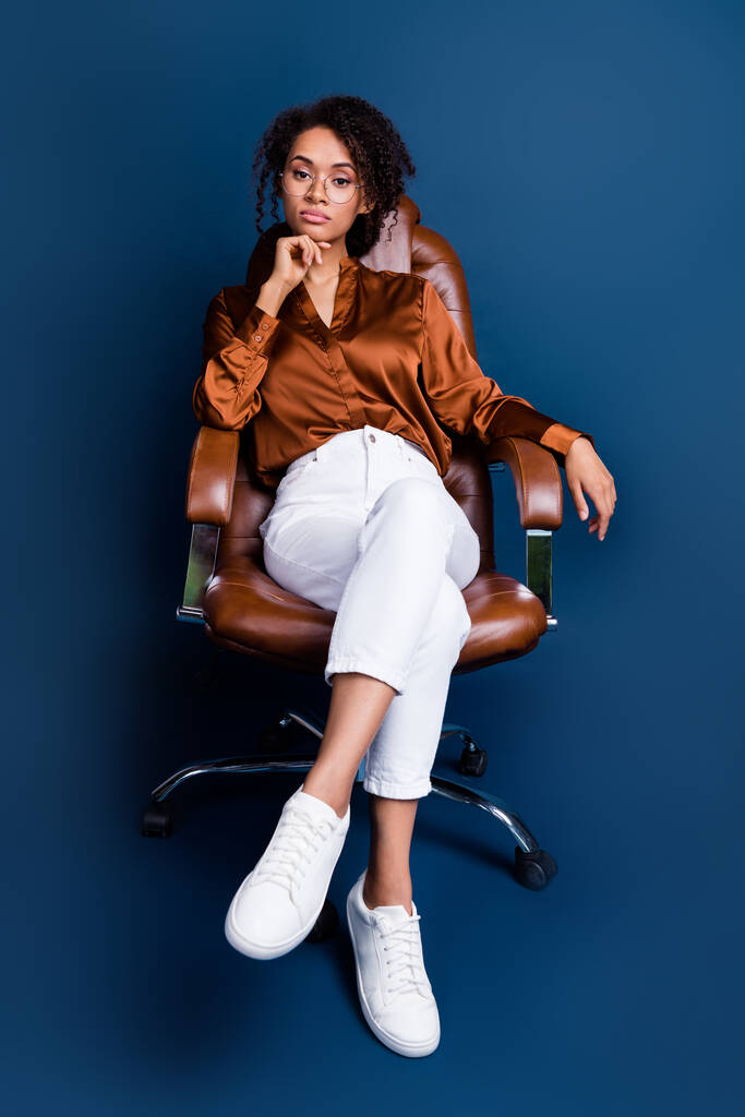 Foto vertical de chica bastante joven estricto jefe sillón trato vestido elegante ropa formal de seda marrón aislado sobre fondo de color azul oscuro. - Foto, imagen
